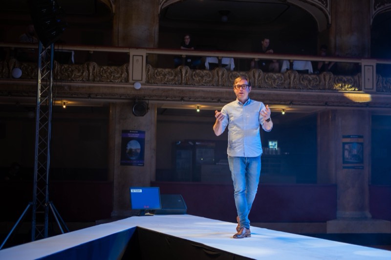 Phil speaking on a long white stage at WebExpo, Prague, with ornate theatre balconies behind